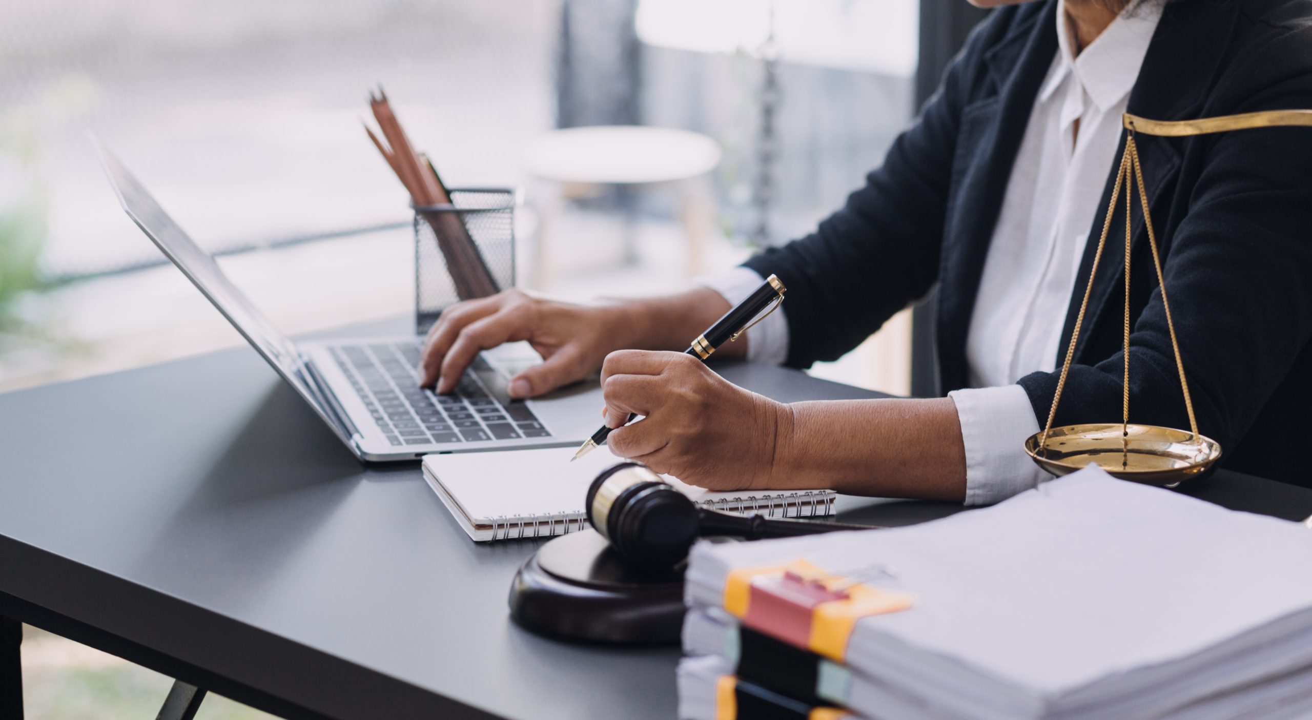 Kash Legal Group: Dedicated Advocacy for Your Case Lawyer working at desk with laptop, notepad, and legal scales, symbolizing thorough case preparation and justice